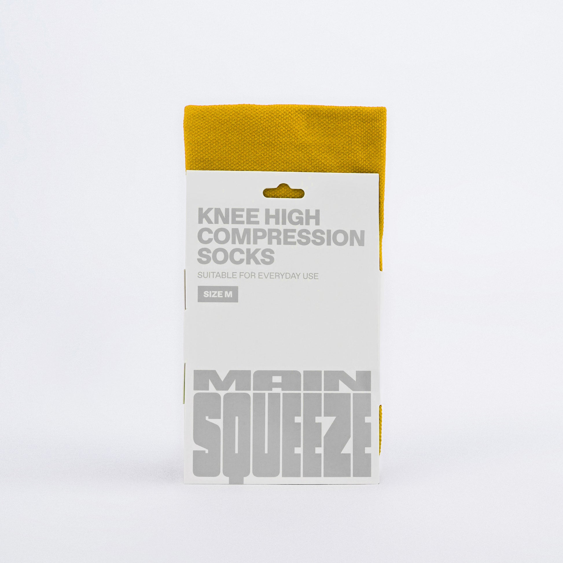 A pair of Main Squeeze yellow knee-high compression socks with a solid pattern.