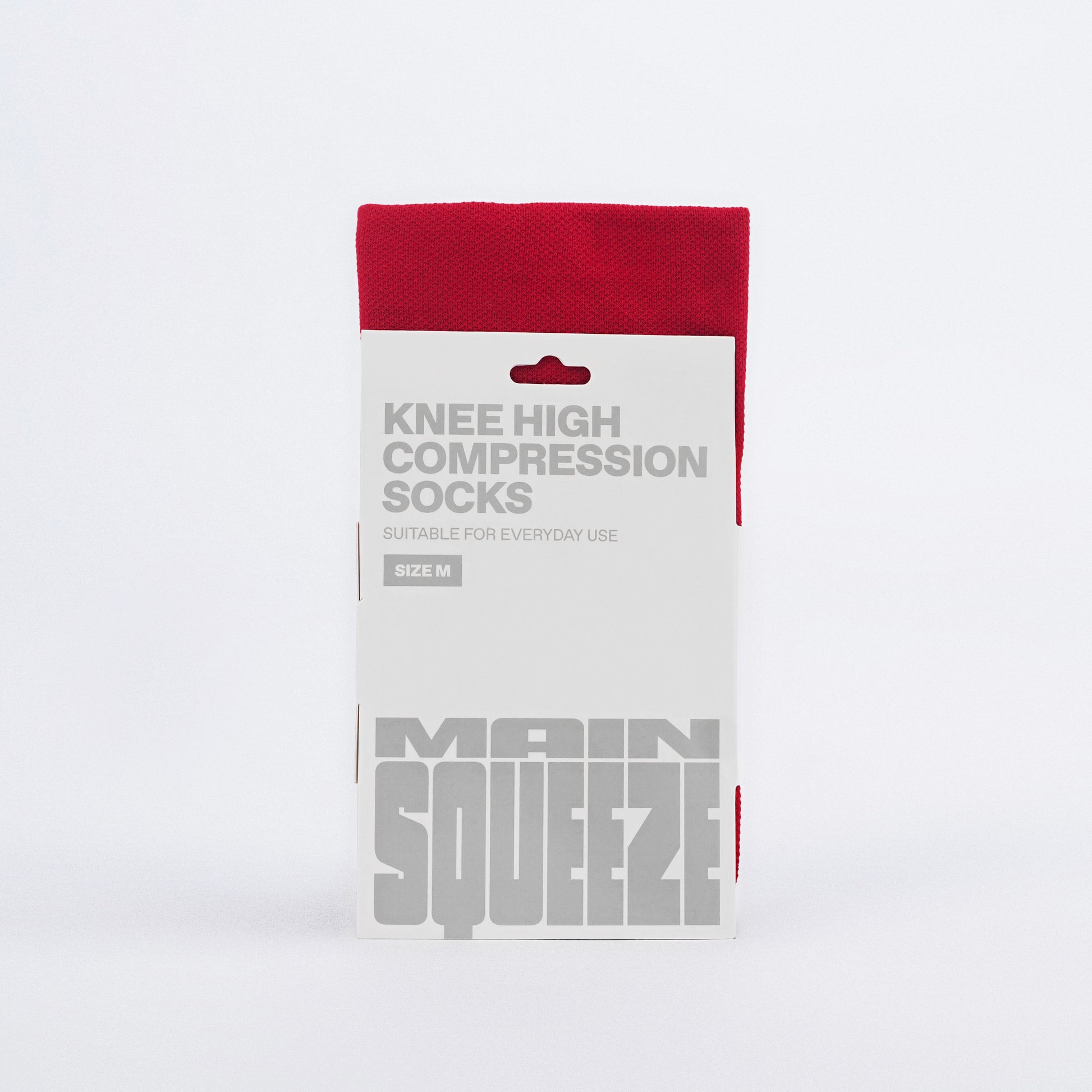 A pair of red knee-high compression socks with text on the cuff.