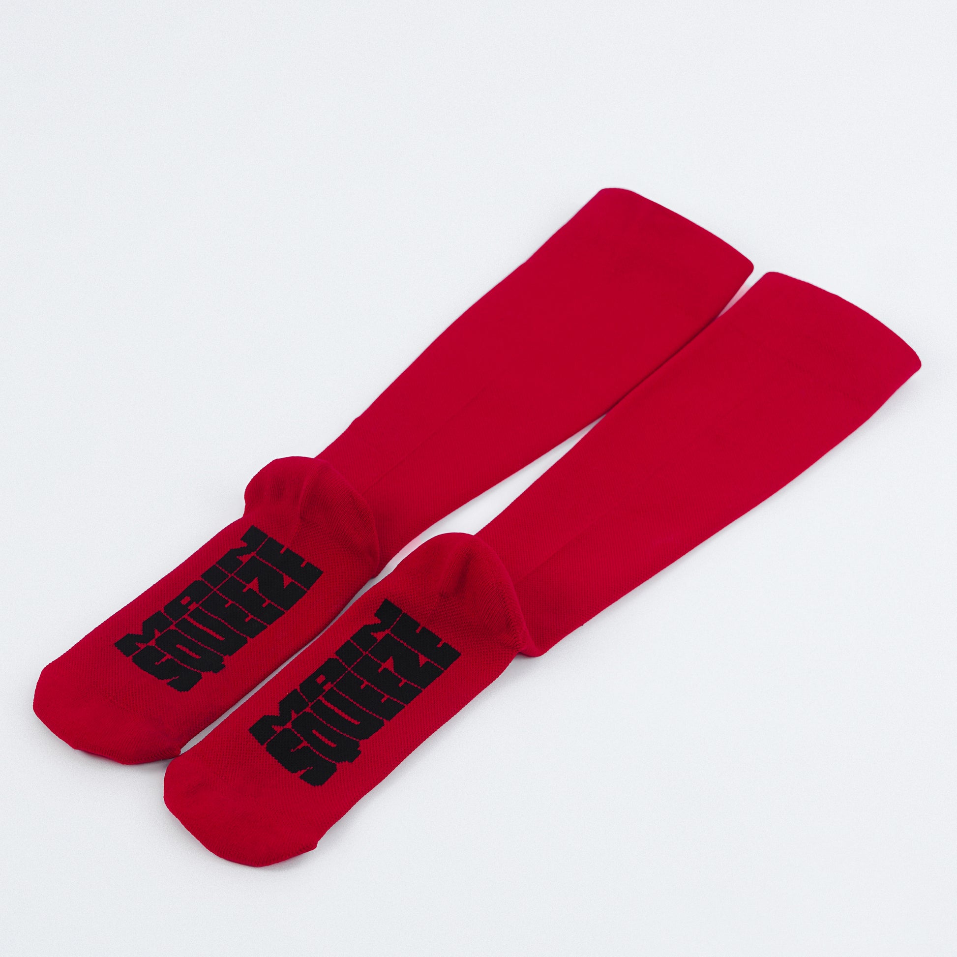 A pair of red knee-high compression socks with text on them, placed against a white background.
